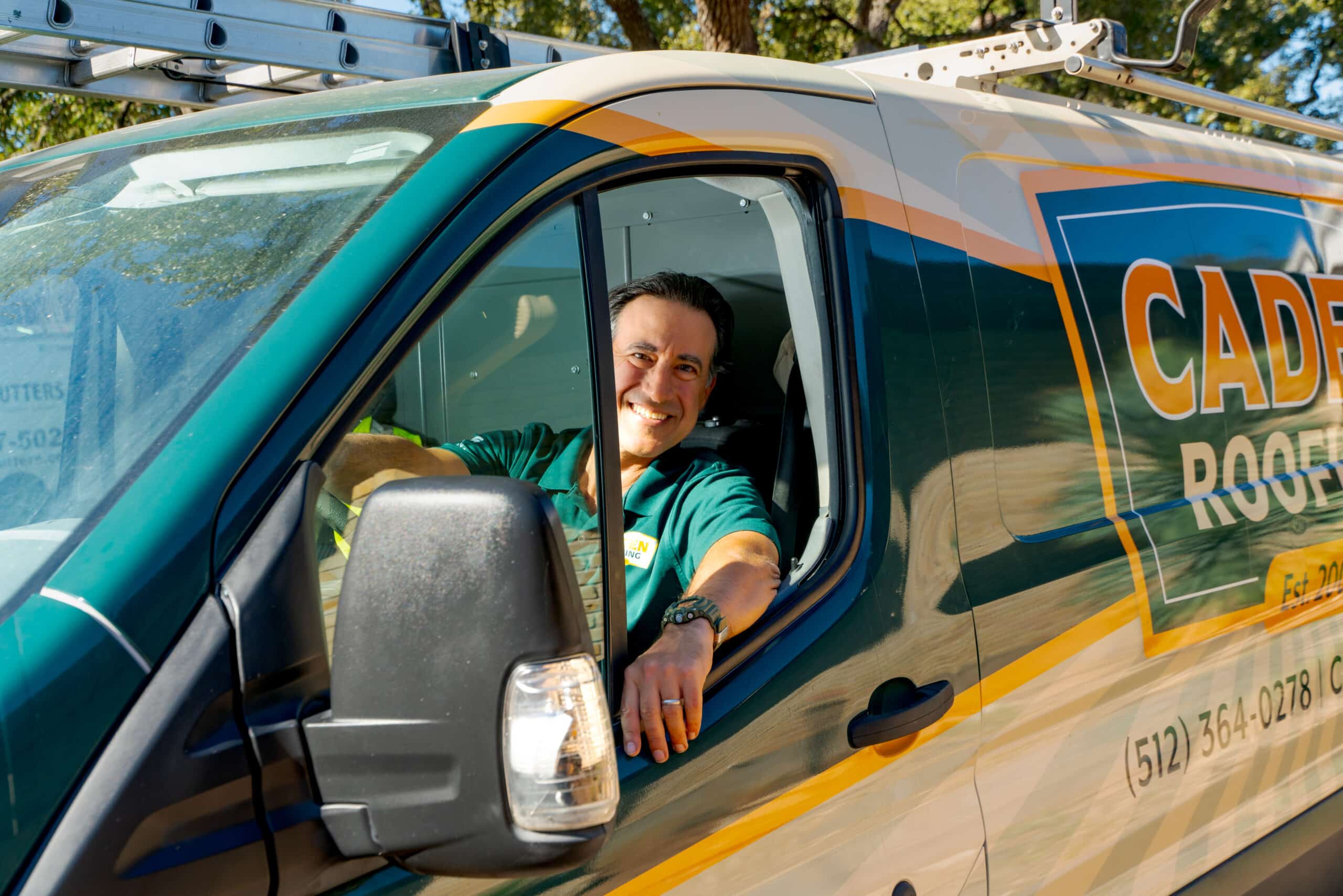 Fareed Tulbah, owner of Caden Roofing, smiling from the driver's seat of a Caden Roofing van